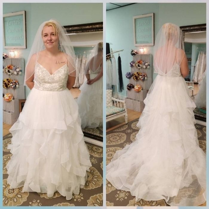 Bridal gown shown front and back in a boutique, featuring a layered white tulle skirt and veil.