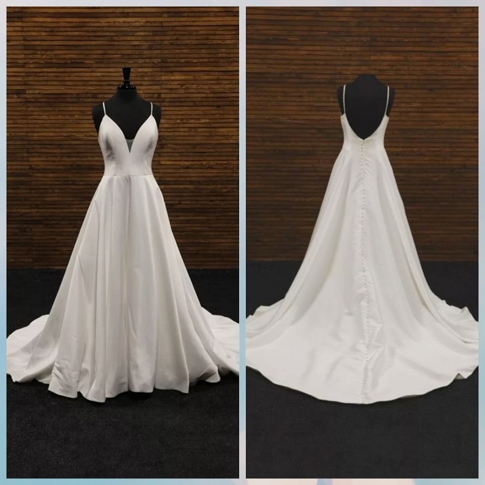 White strapless wedding gown displayed front and back on a black mannequin against a wood wall.