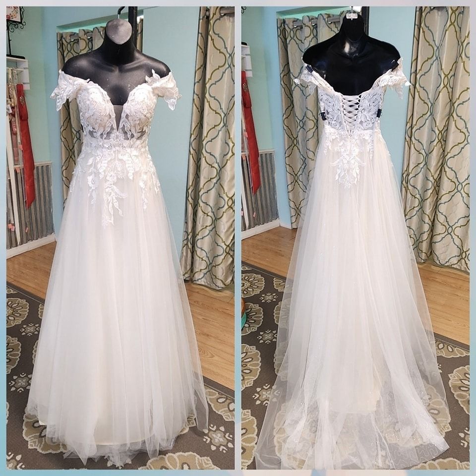 White lace and tulle wedding gown displayed on a black mannequin, front and back views.