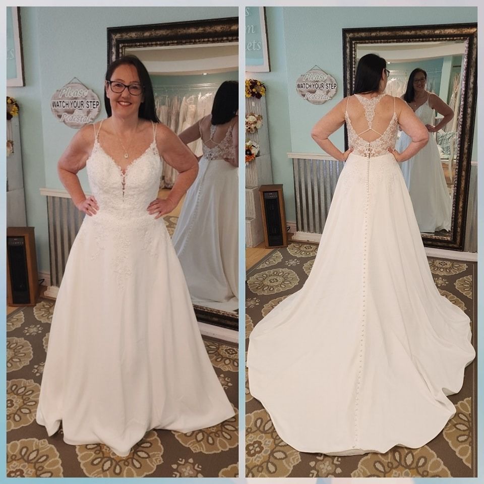 Woman in a white wedding dress, front and back views in a mirror-lit room.