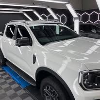 A white truck is parked on a lift in a garage.