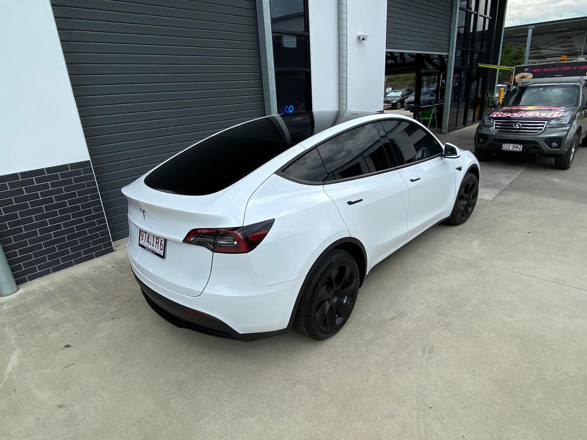 A white tesla model y is parked in front of a building.