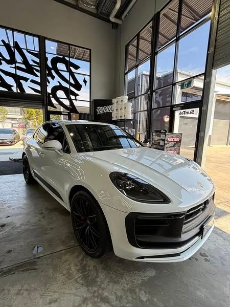 A white porsche macan turbo is parked in a garage.