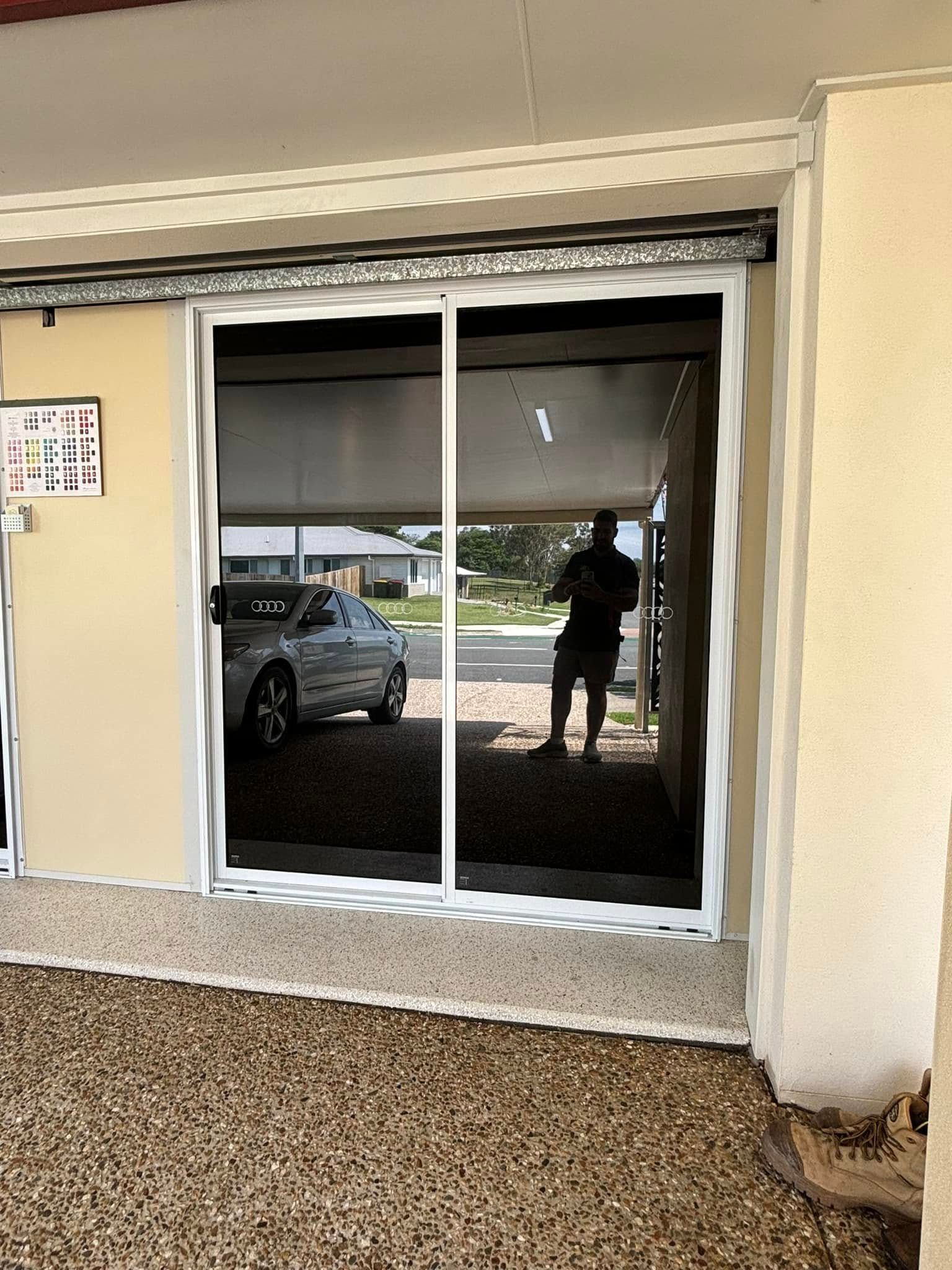 A man is standing in front of a sliding glass door.