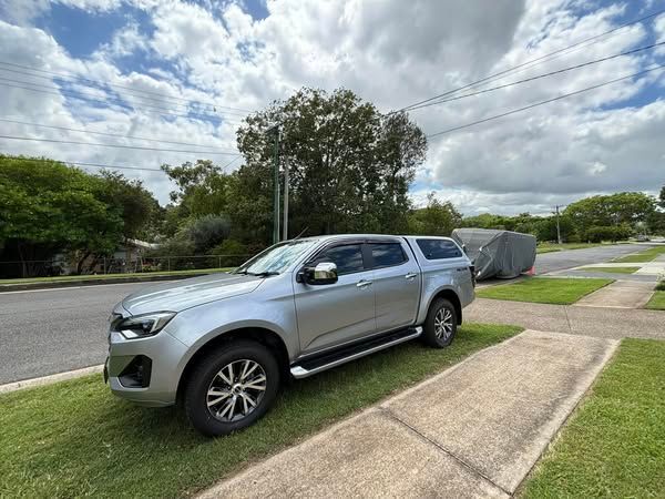 A silver truck with a canopy is parked on the side of the road.