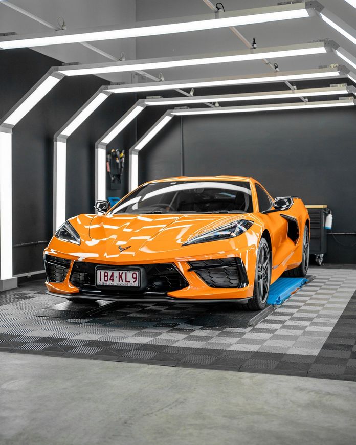 An orange sports car is parked in a garage.