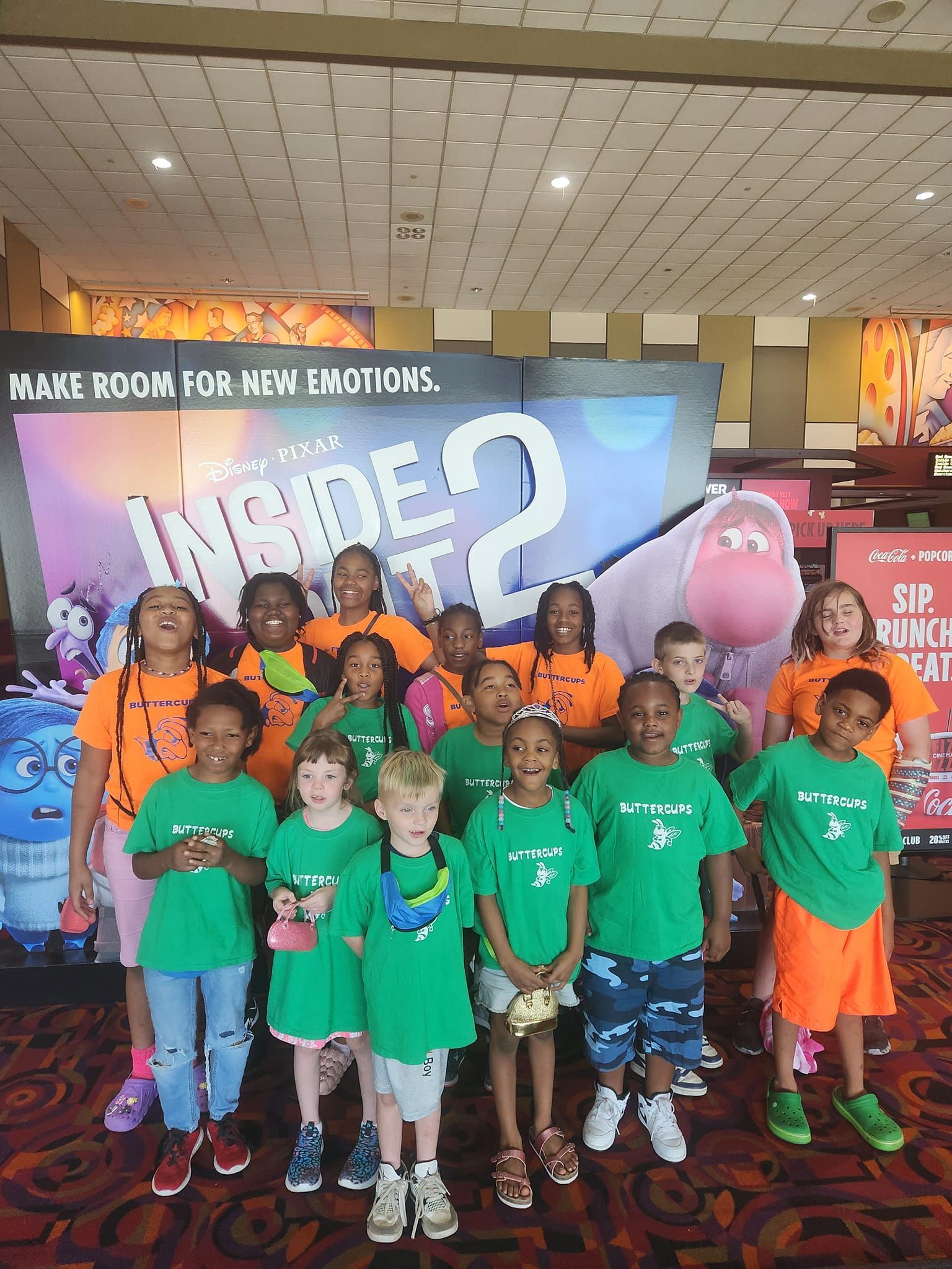 A group of children posing for a photo in front of a colorful Inside Out 2 movie display.