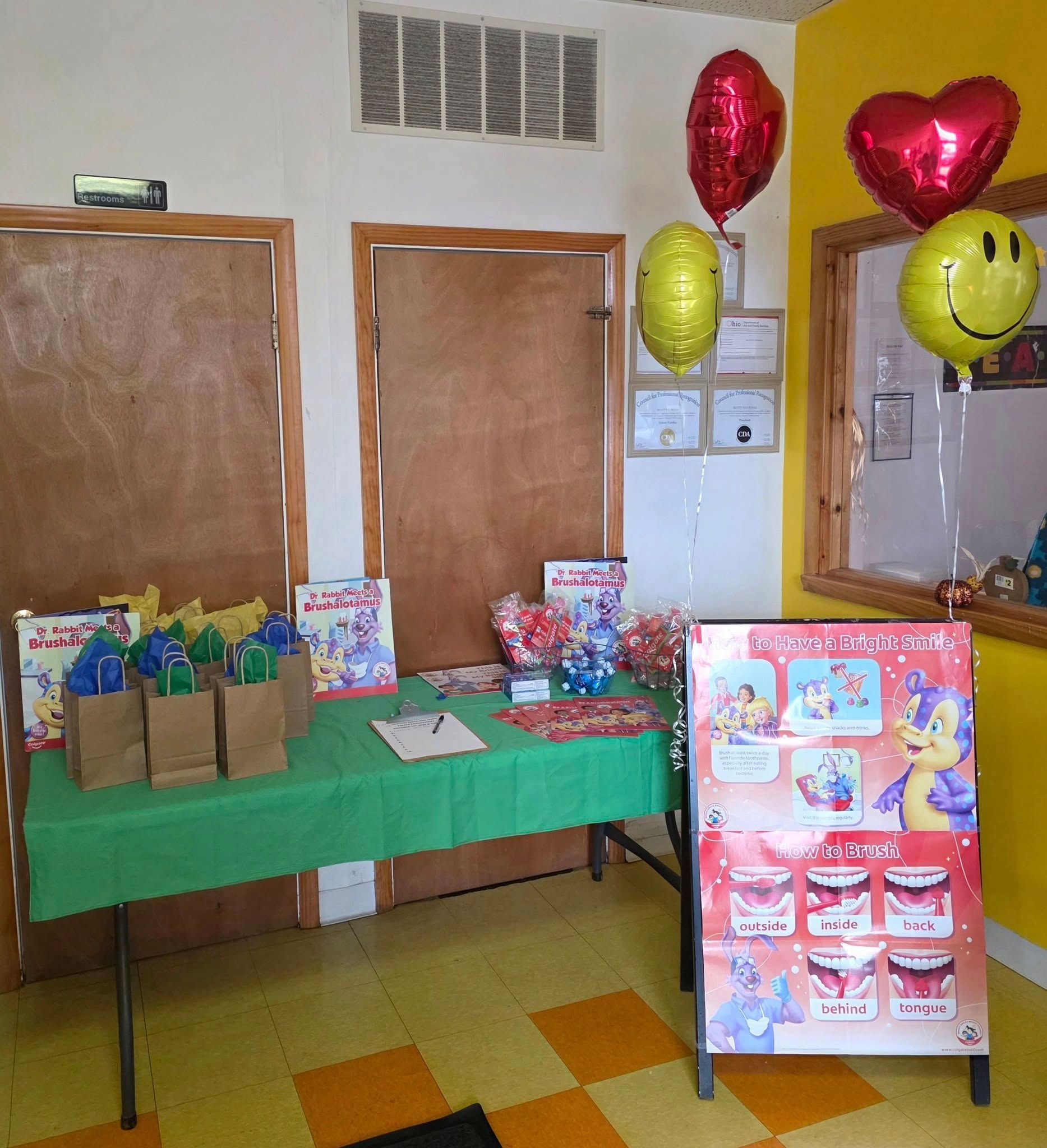 A party table with gift bags and an Alvin and the Chipmunks sign, decorated with red heart and yellow smiley balloons.