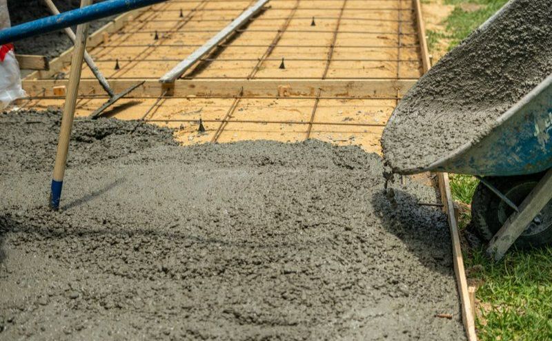 A Person is Pouring Concrete Into a Wheelbarrow — Turnscape Landscaping In Broadbeach, QLD