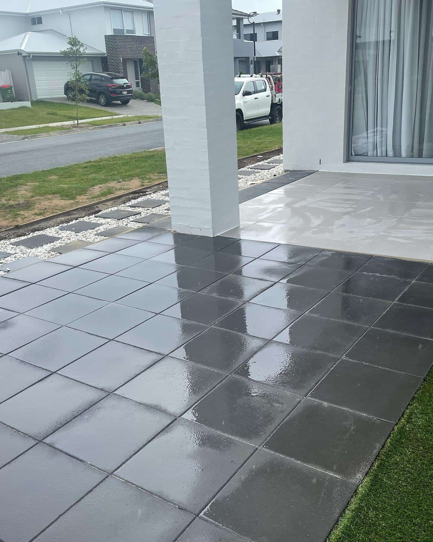 A patio with a car parked in the background and a reflection of a car in the tiles. — Turnscape Landscaping In Broadbeach, QLD