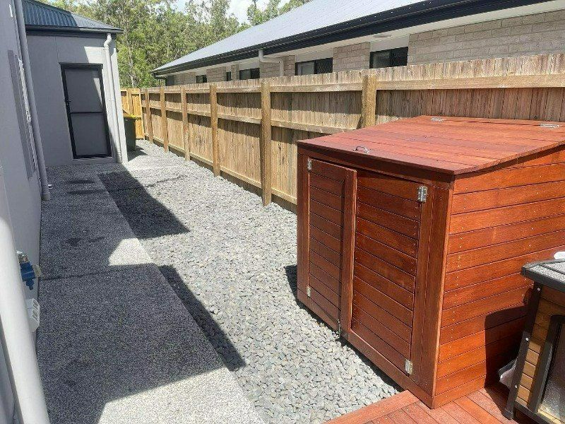 A Wooden Shed is Sitting Next to a Wooden Fence — Turnscape Landscaping in Beechmont, QLD