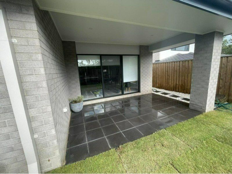 A Patio With a Sliding Glass Door in the Backyard of a House — Turnscape Landscaping in Robina, QLD