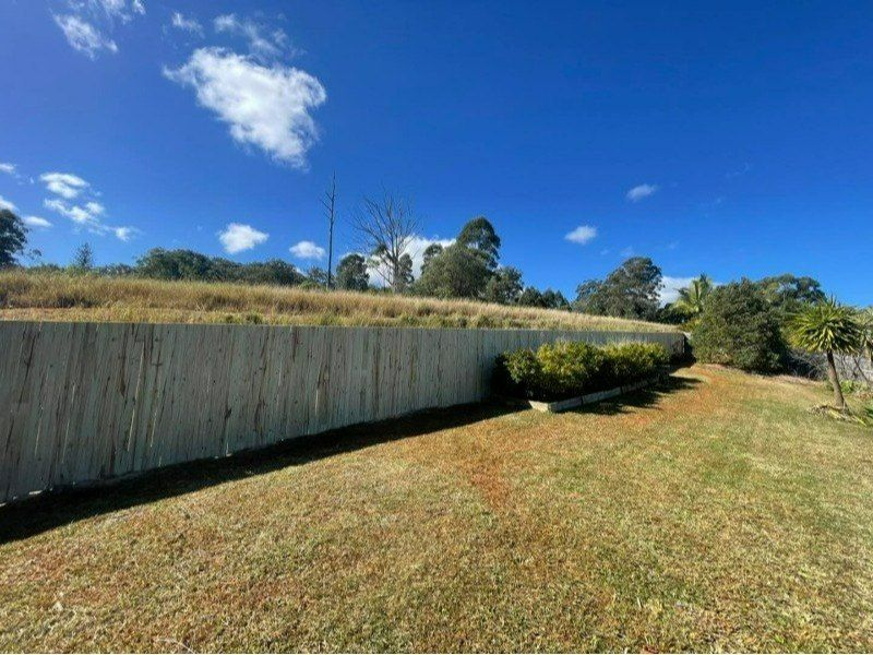 A Wooden Fence Surrounds a Grassy Field on a Sunny Day — Turnscape Landscaping in Burleigh Heads, QLD