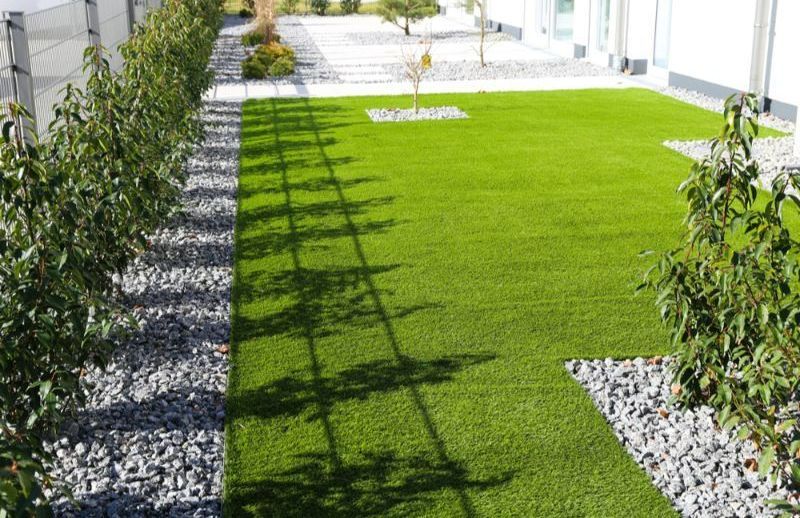 A Man is Rolling a Roll of Turf on a Lawn — Turnscape Landscaping in Palm Beach, QLD