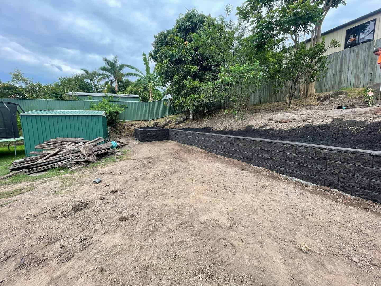 A backyard with a fence and a green shed in the background. — Turnscape Landscaping In Broadbeach, QLD