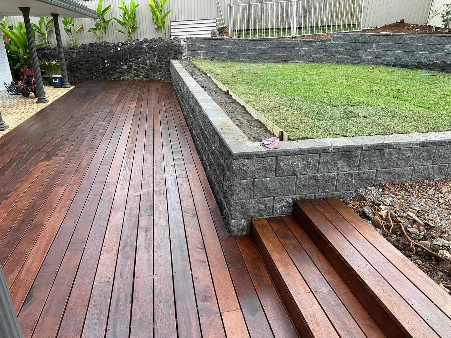 A wooden deck with stairs leading up to it in a backyard. — Turnscape Landscaping in Mudgeeraba, QLD