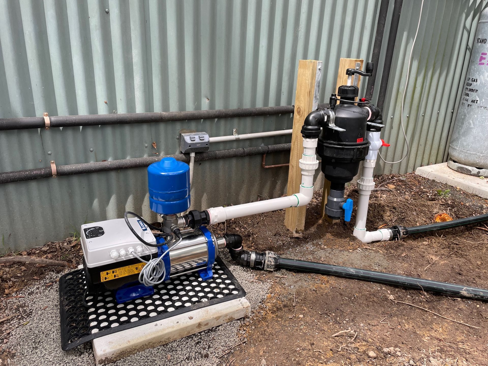 A water pump is sitting in the dirt next to a fence- Irrigation Solutions in Southern Highlands, NSW