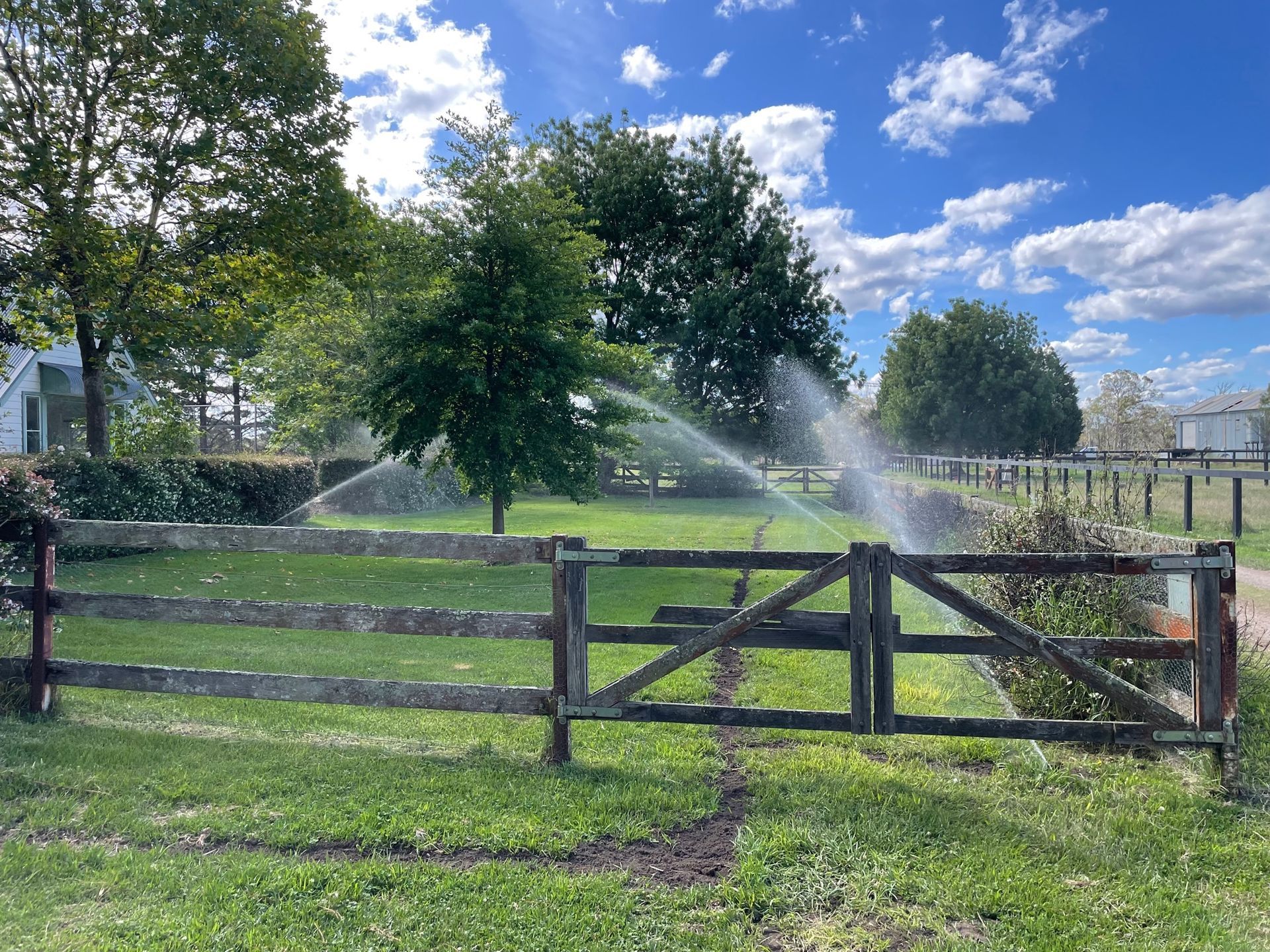 A wooden fence is surrounded by a lush green field- Irrigation Solutions in Southern Highlands, NSW