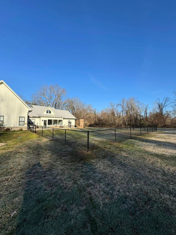 Snowy backyard with a house, leafless trees, and a clear blue sky