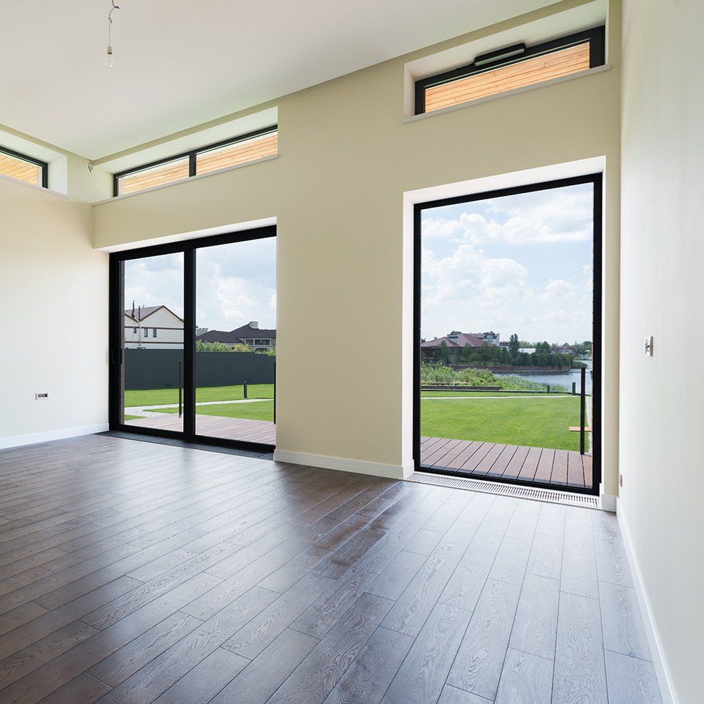 An empty room with hardwood floors and sliding glass doors.