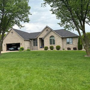 A large brick house with a lush green lawn in front of it.