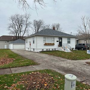 A white house with a gray roof is for sale.