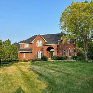 A large brick house with a lush green lawn in front of it.
