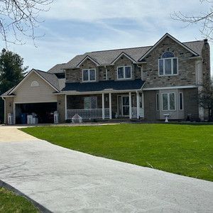 A large brick house with a lush green lawn and a driveway leading to it.