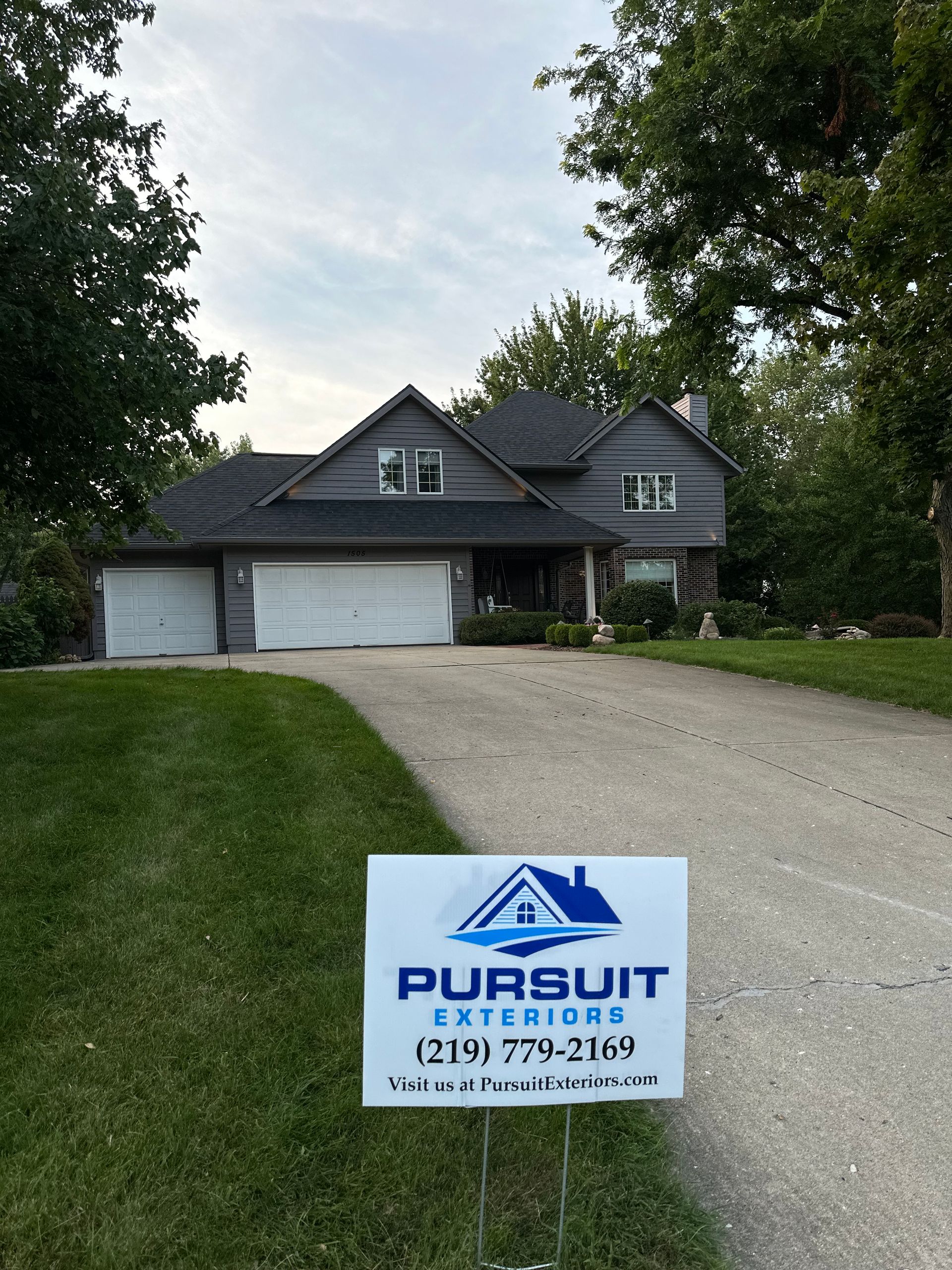 A house with a sign in front of it that says pursuit exteriors