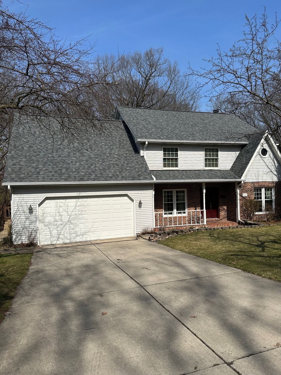 A white house with a gray roof and a white garage door.