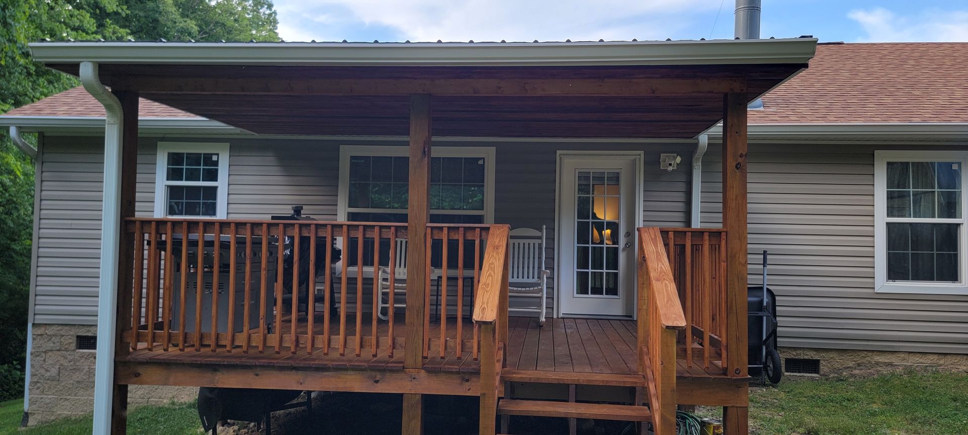 A small house with a wooden porch and stairs in front of it.