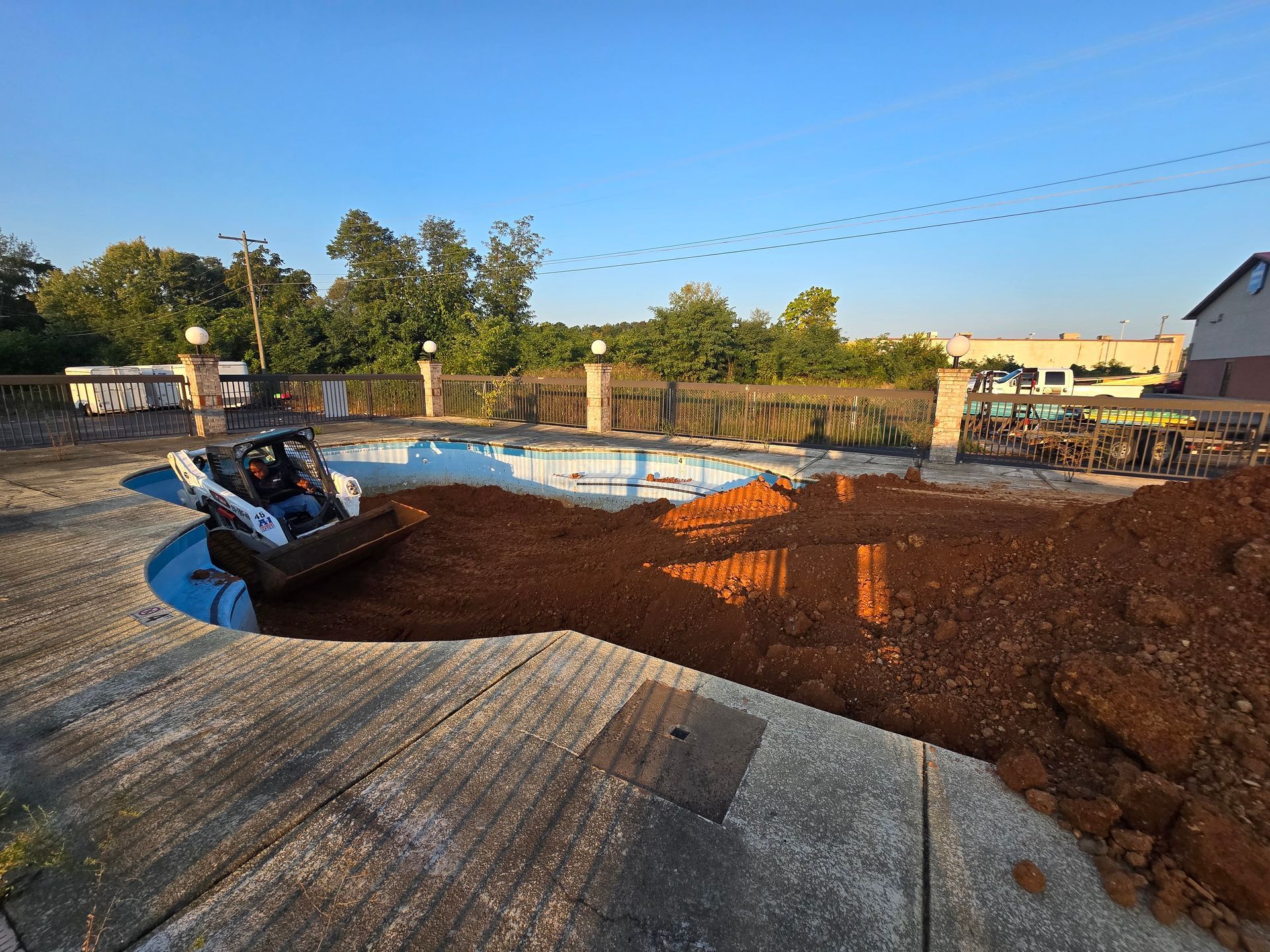 A bulldozer is moving dirt around a swimming pool.