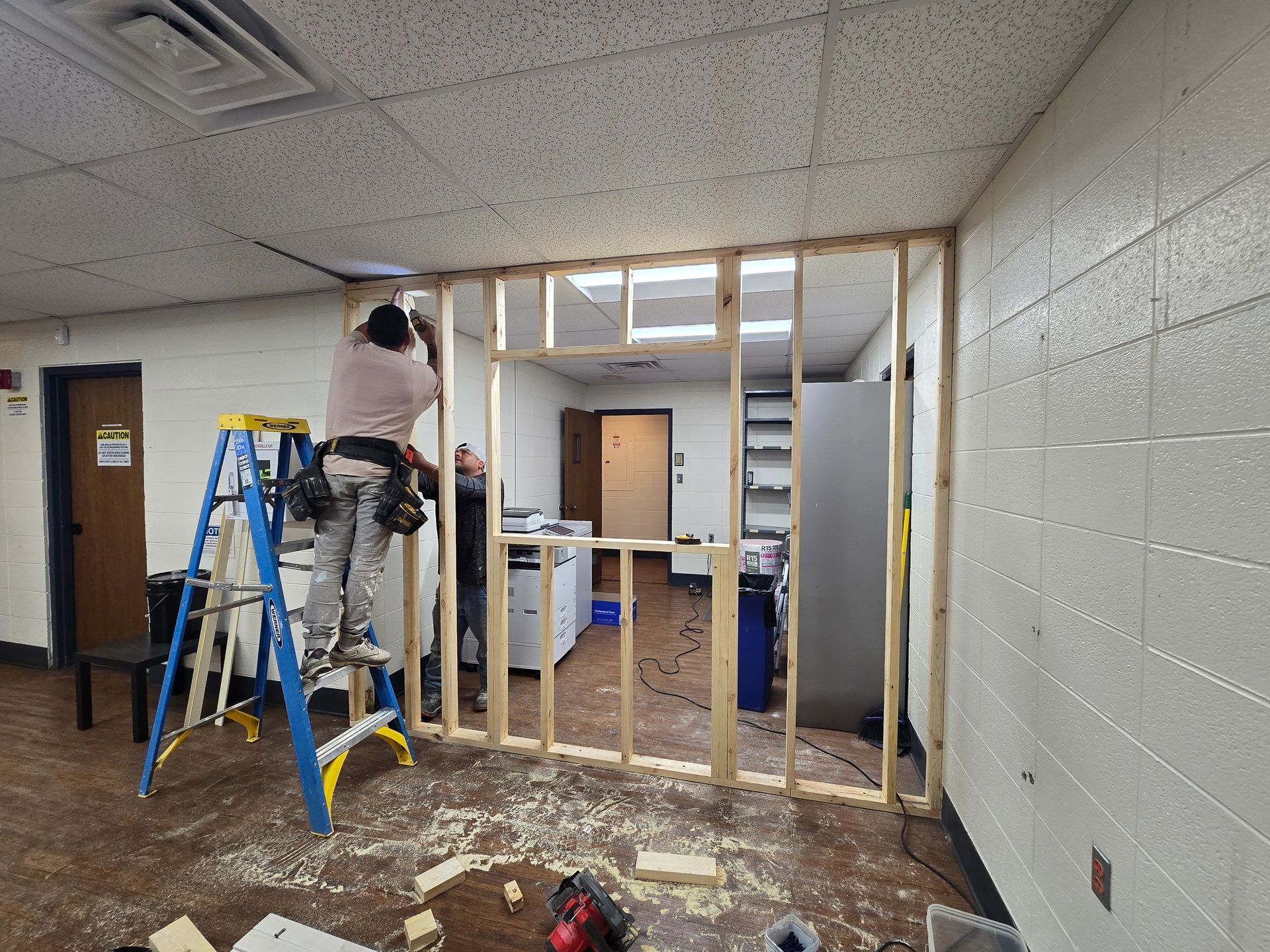 A man is standing on a ladder in a room.