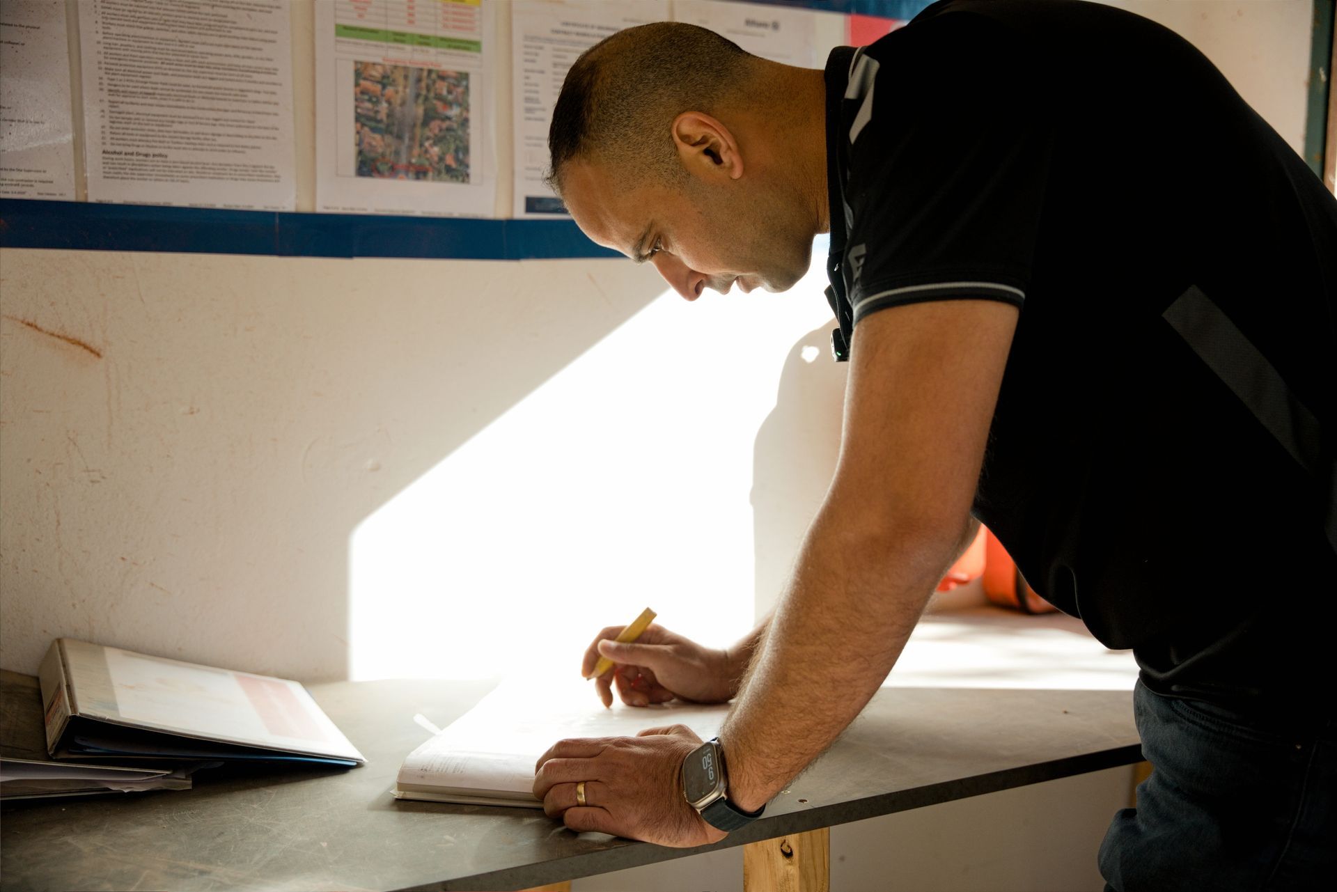 Two men in black shirts inspecting a damaged ceiling in a room under renovation