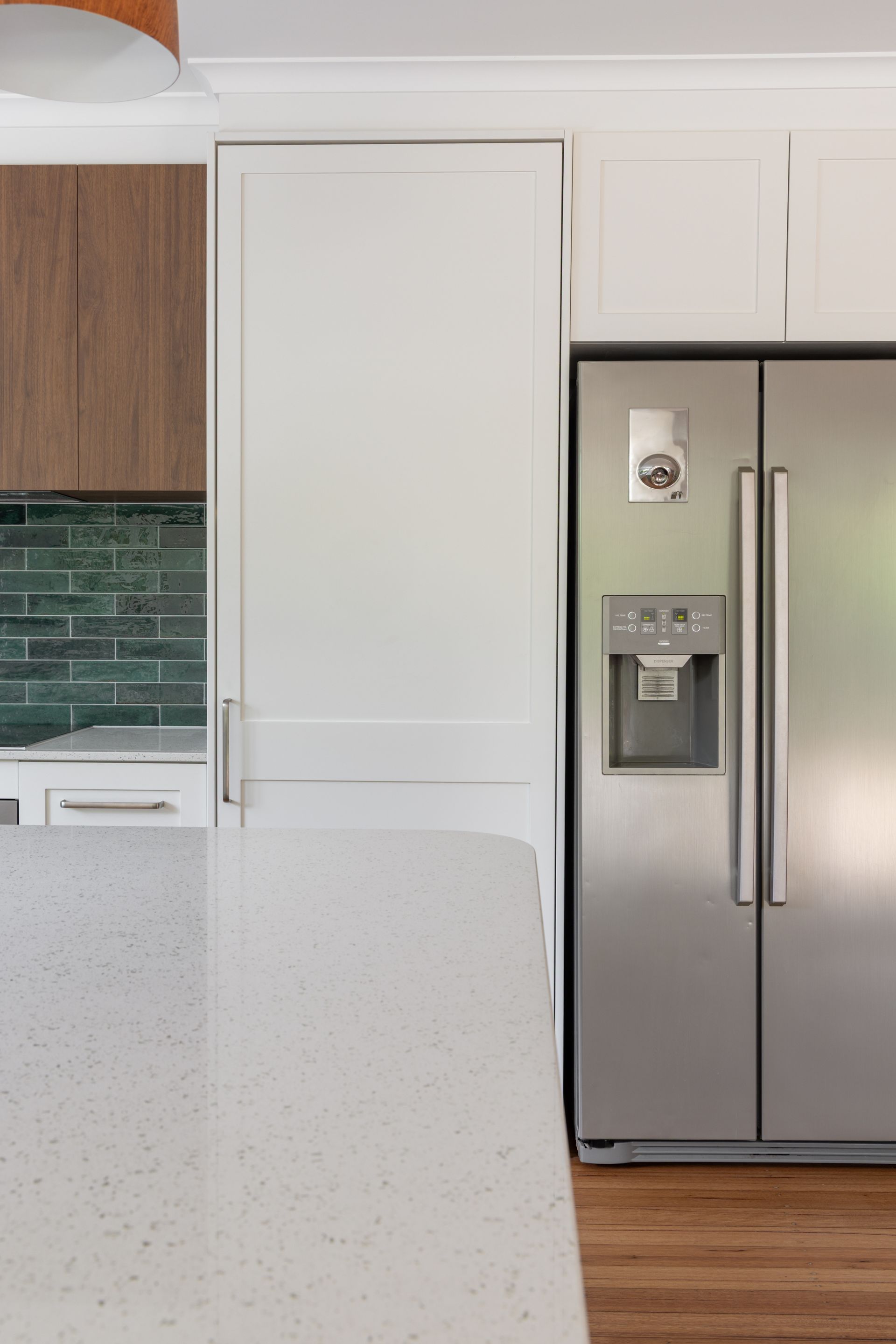 Modern kitchen with white cabinets, stainless steel refrigerator, and speckled countertop
