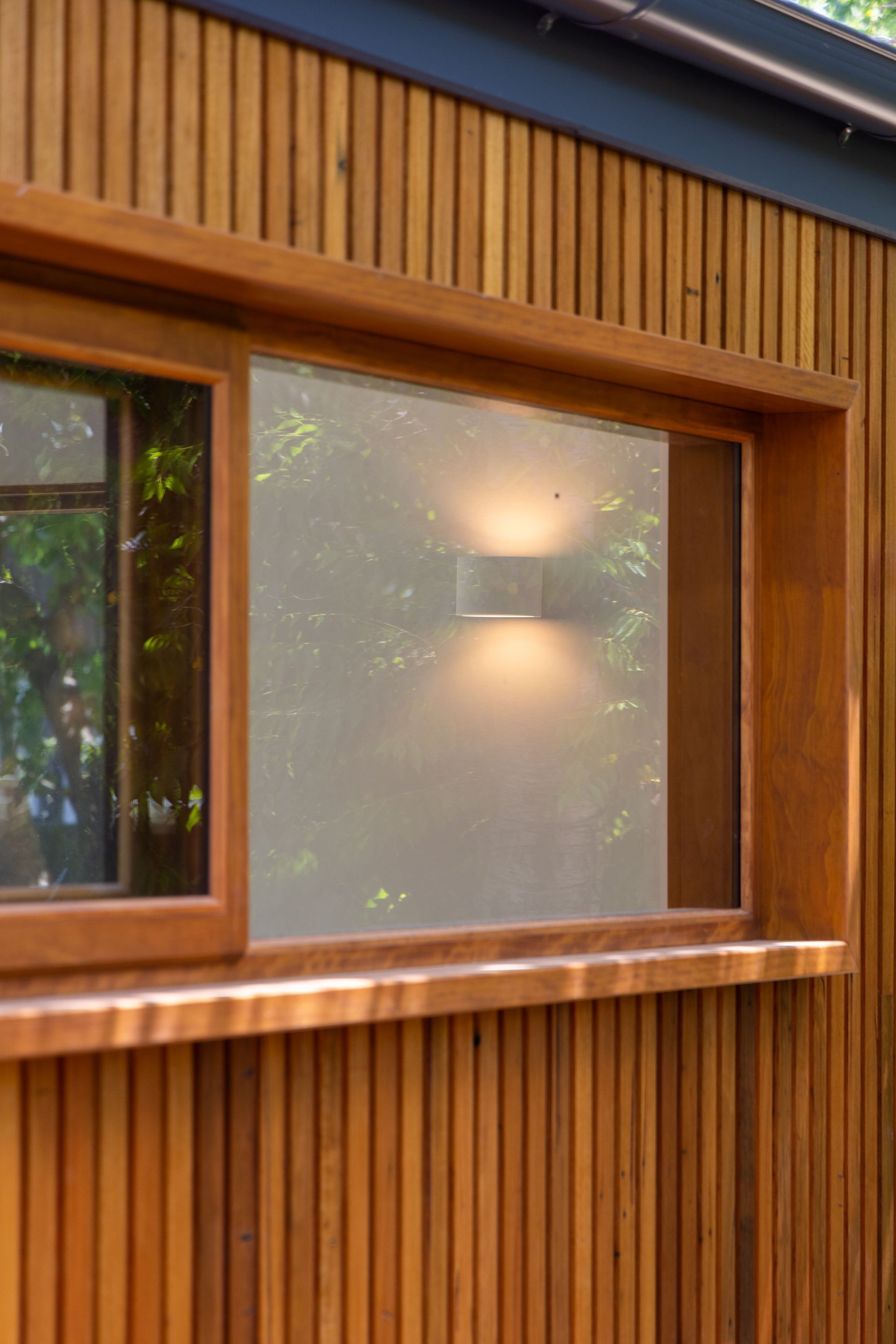 Wooden house exterior with a frosted window and warm light glowing inside