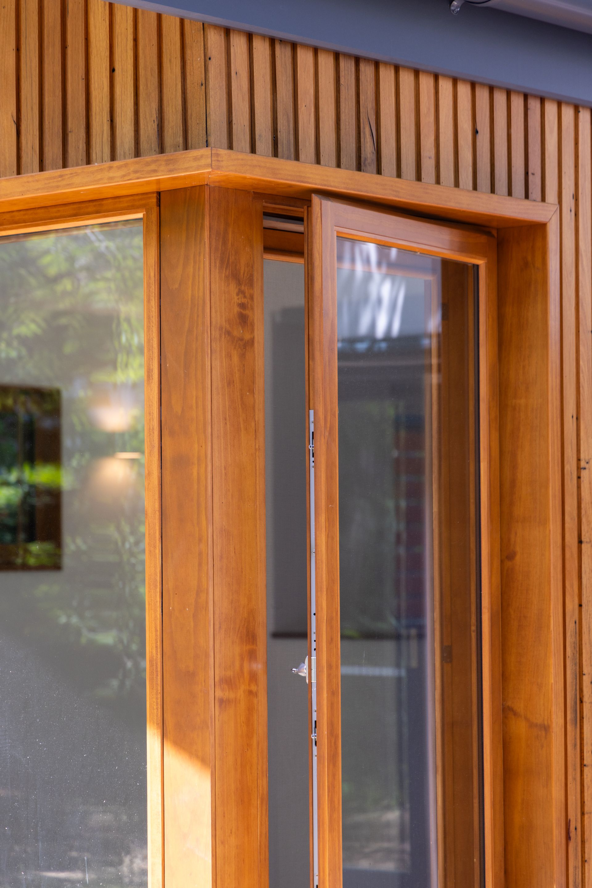 Wooden-framed glass door on the exterior of a building with vertical wood siding