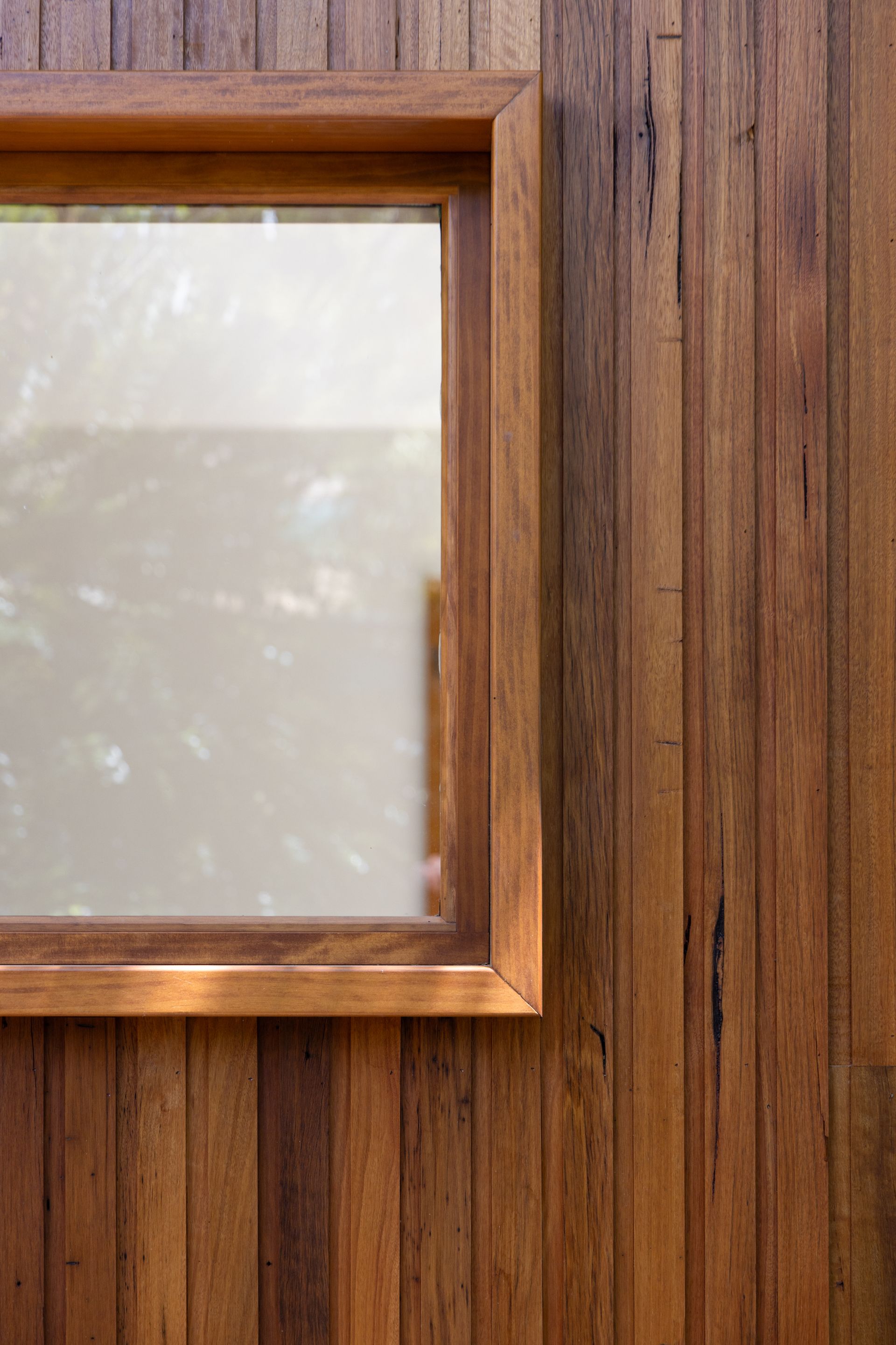 Close-up of a wooden wall with a frosted glass window framed in light wood.