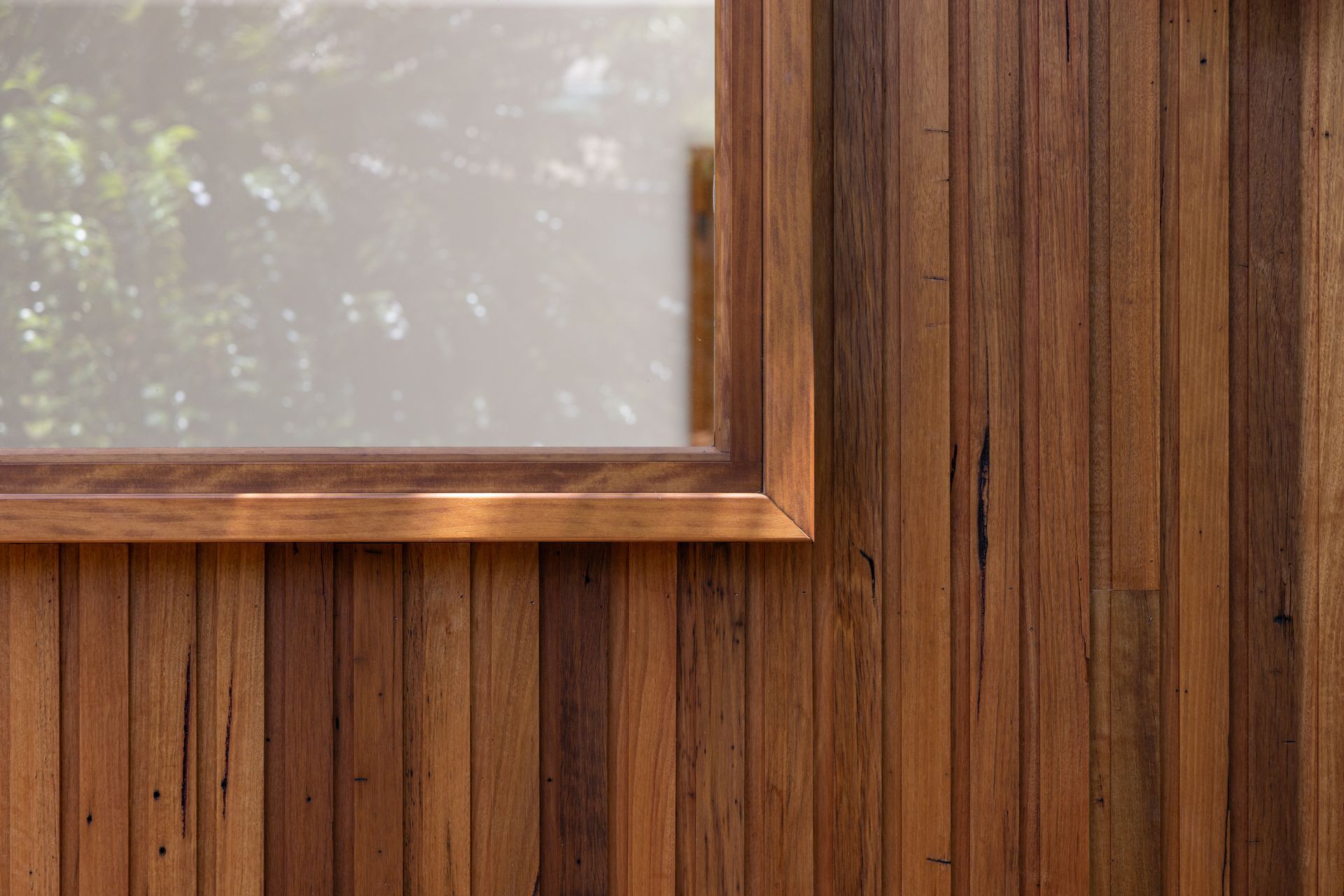 Wood-paneled wall with a framed window showing blurred greenery outside