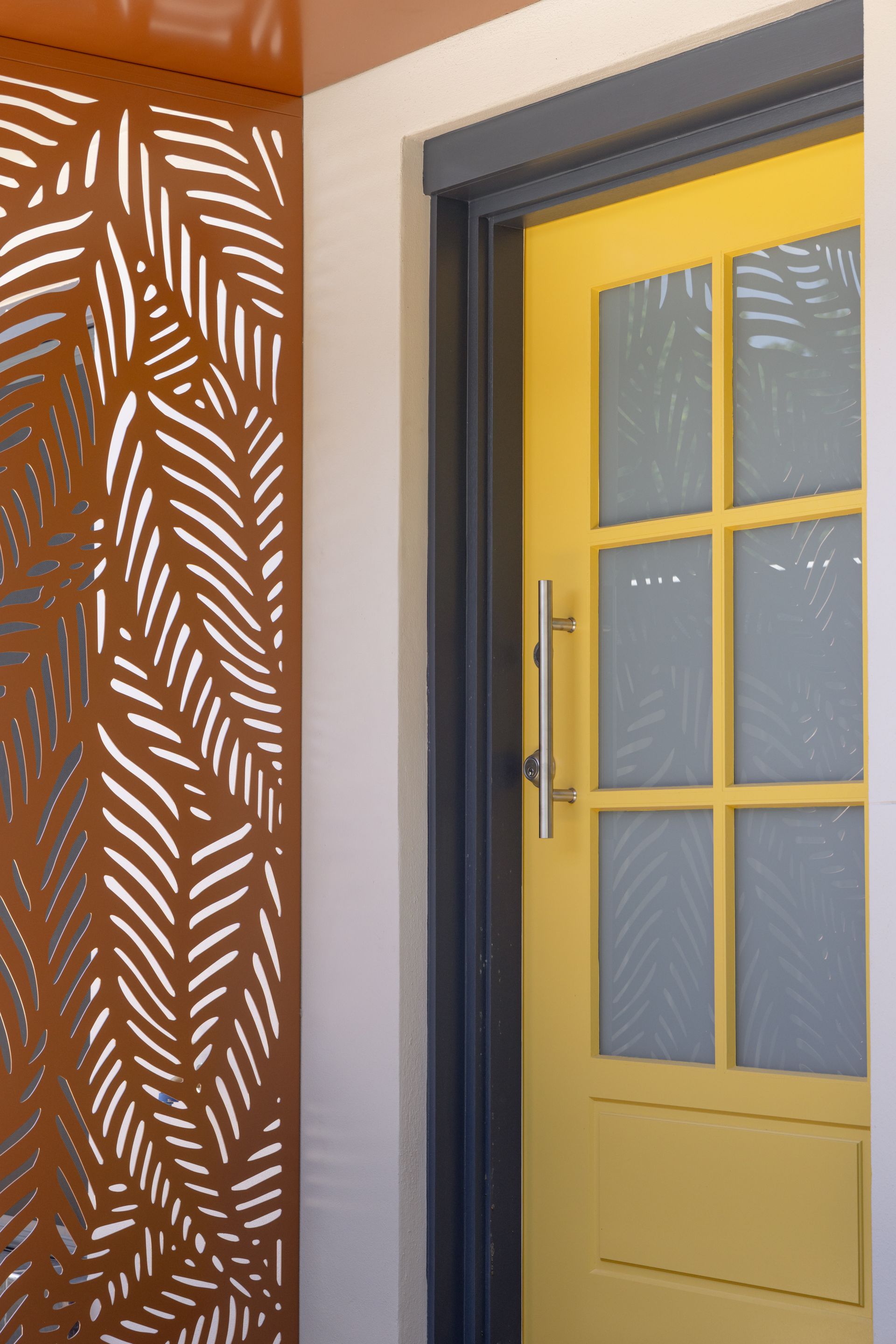 Yellow door with glass panes beside a brown patterned wall panel