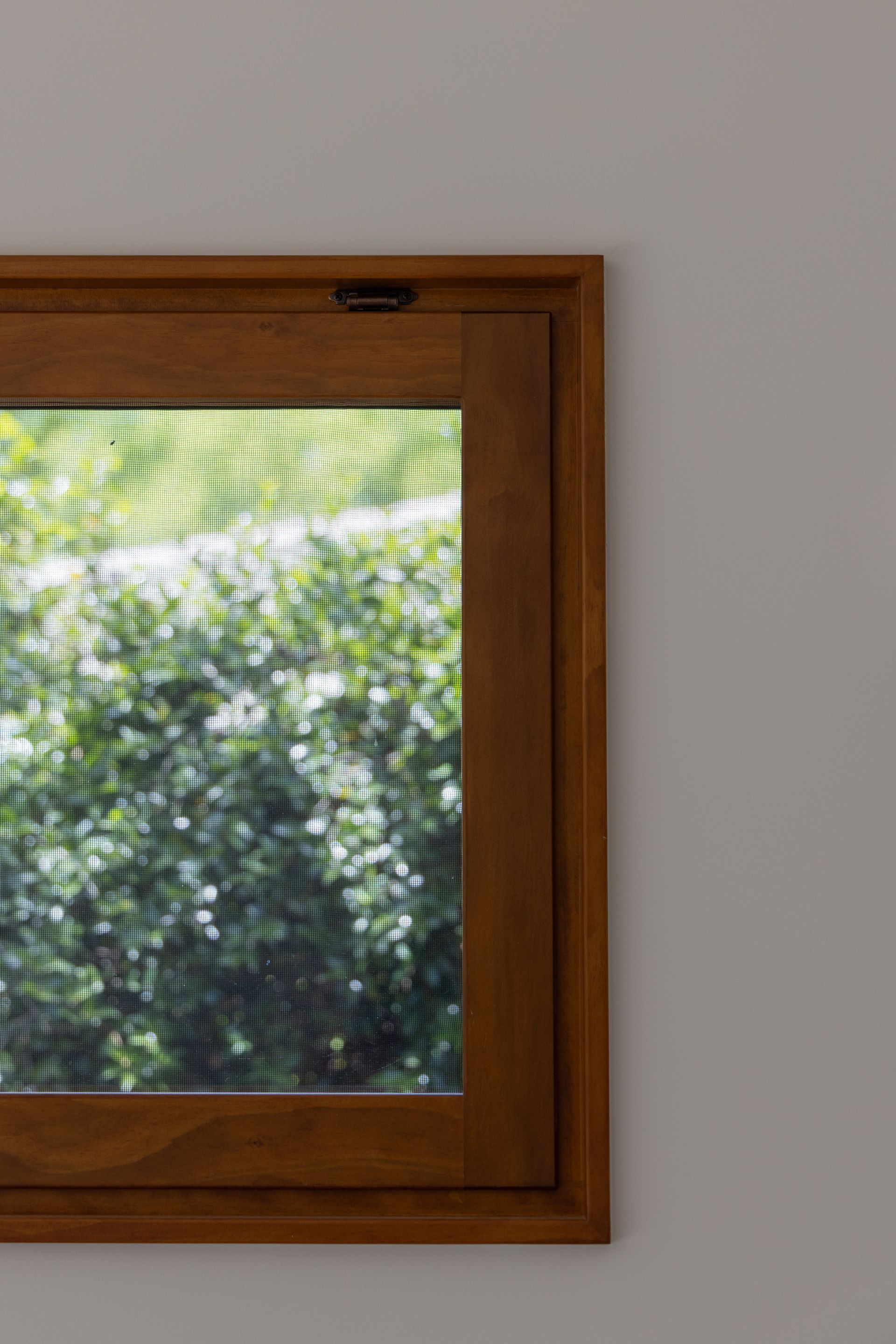Wooden-framed window with frosted glass and a gray wall beside it