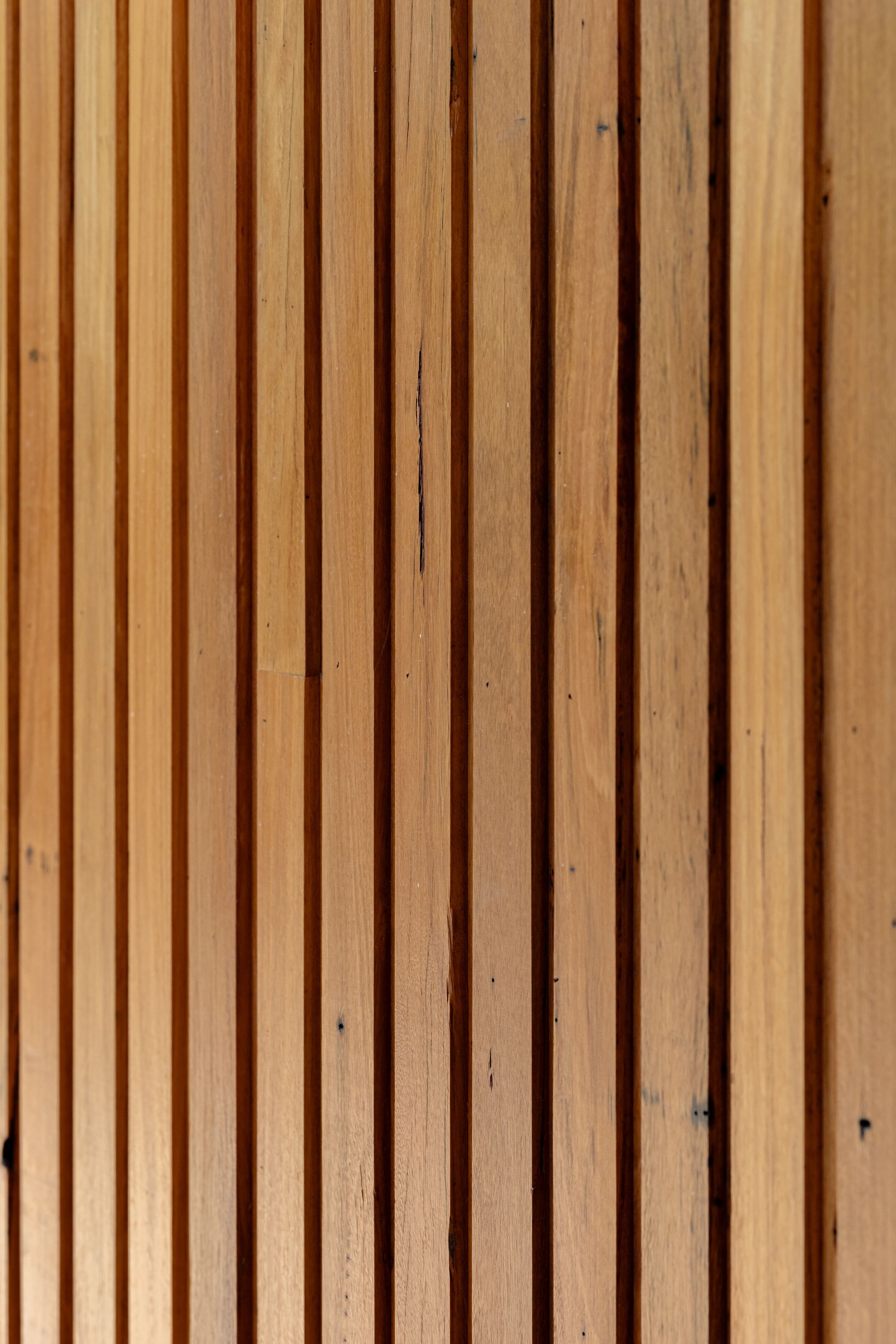 Vertical wooden slats in light and dark brown tones, forming a textured panel