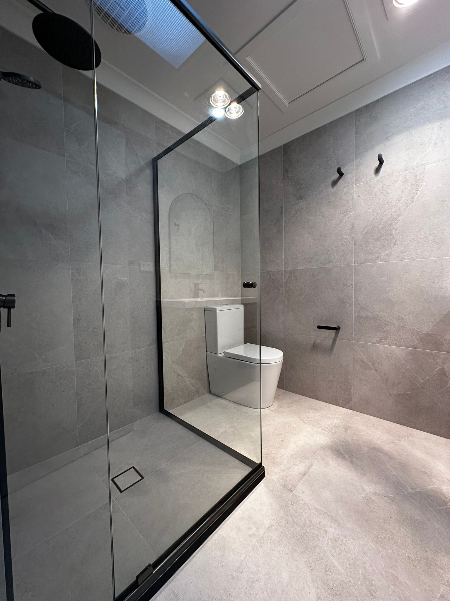 Modern gray bathroom with glass shower enclosure and white toilet