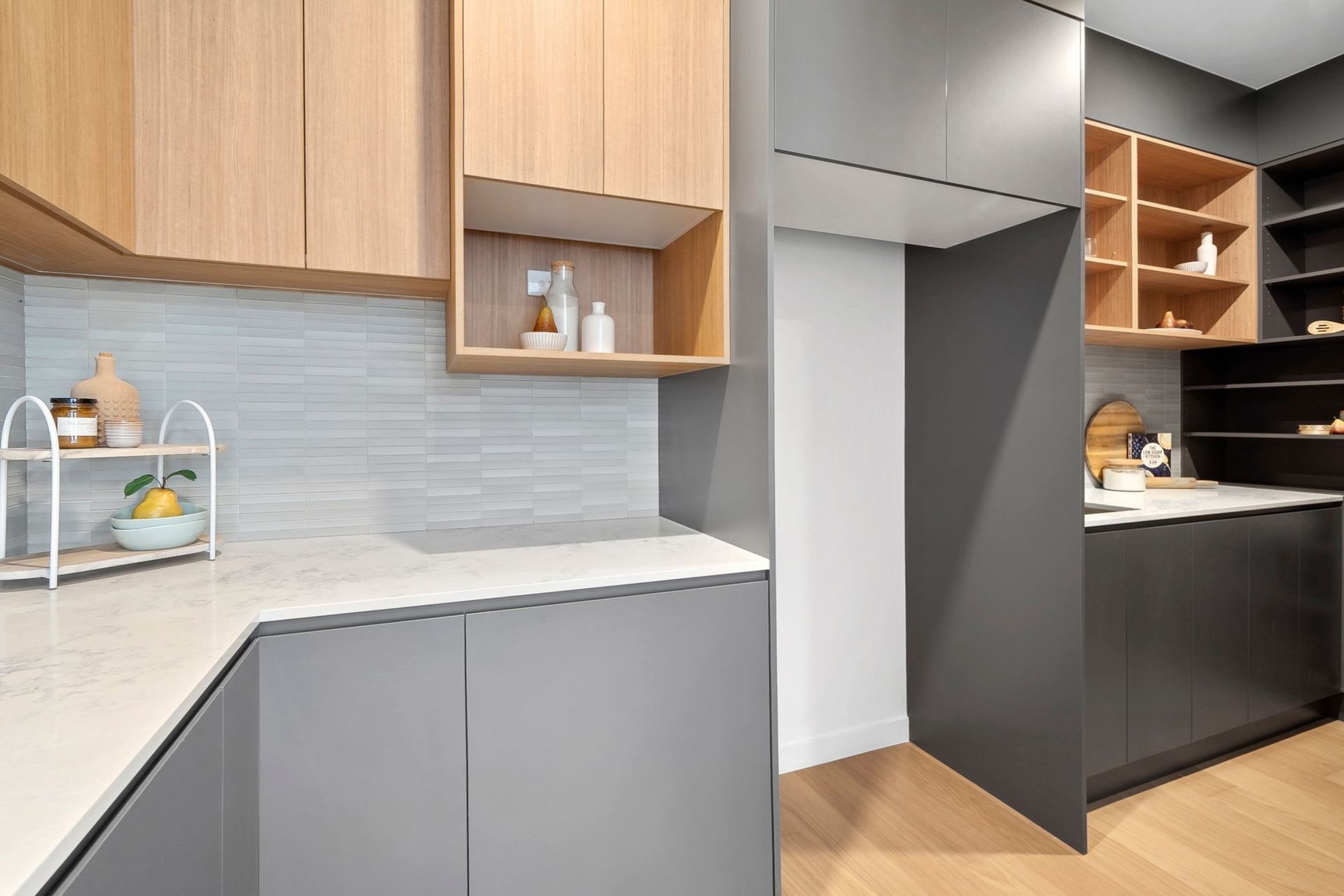 Modern kitchen with gray cabinets, wood accents, and open shelving beside a pantry area