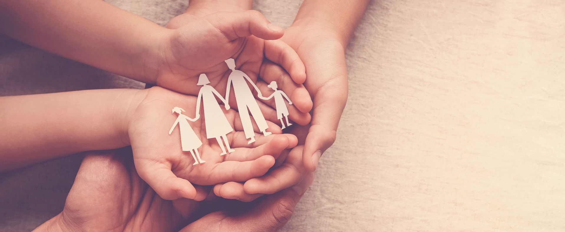 Hands holding small white paper figures in a circle, symbolizing teamwork and community