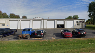 A row of cars are parked in front of a building.