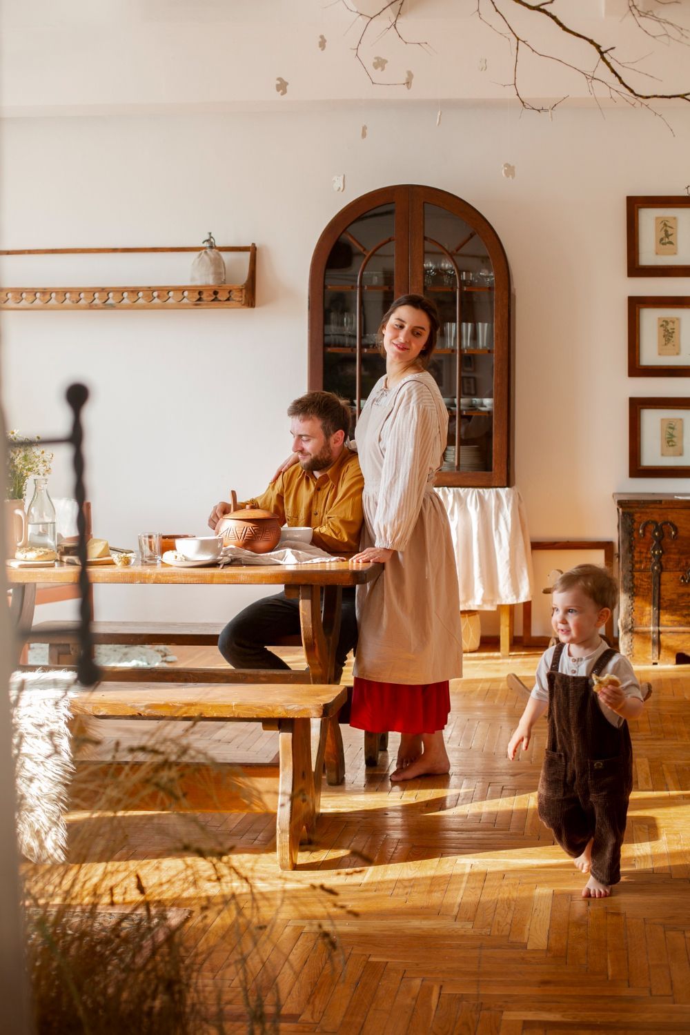 Cozy dining room with a family at the table, warm sunlight, and a child walking in the foreground