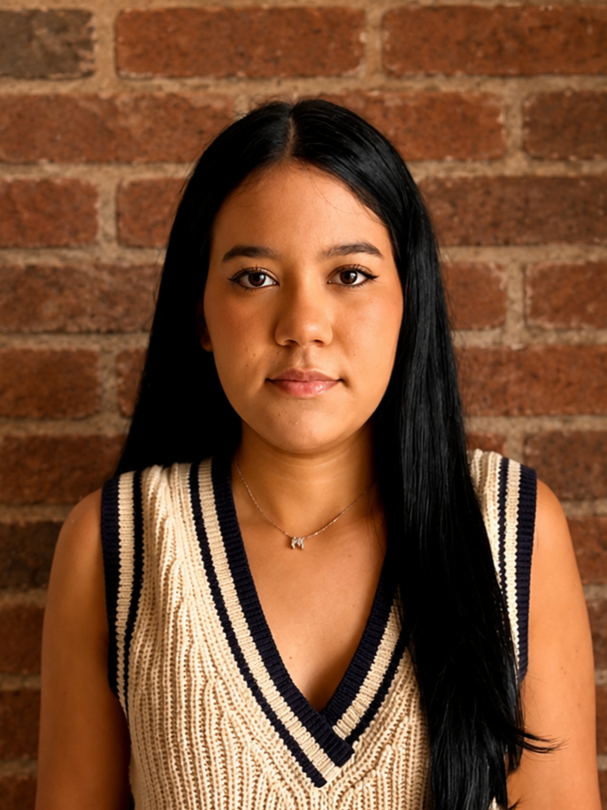 Portrait of a woman with long black hair wearing a striped V-neck top against a brick wall