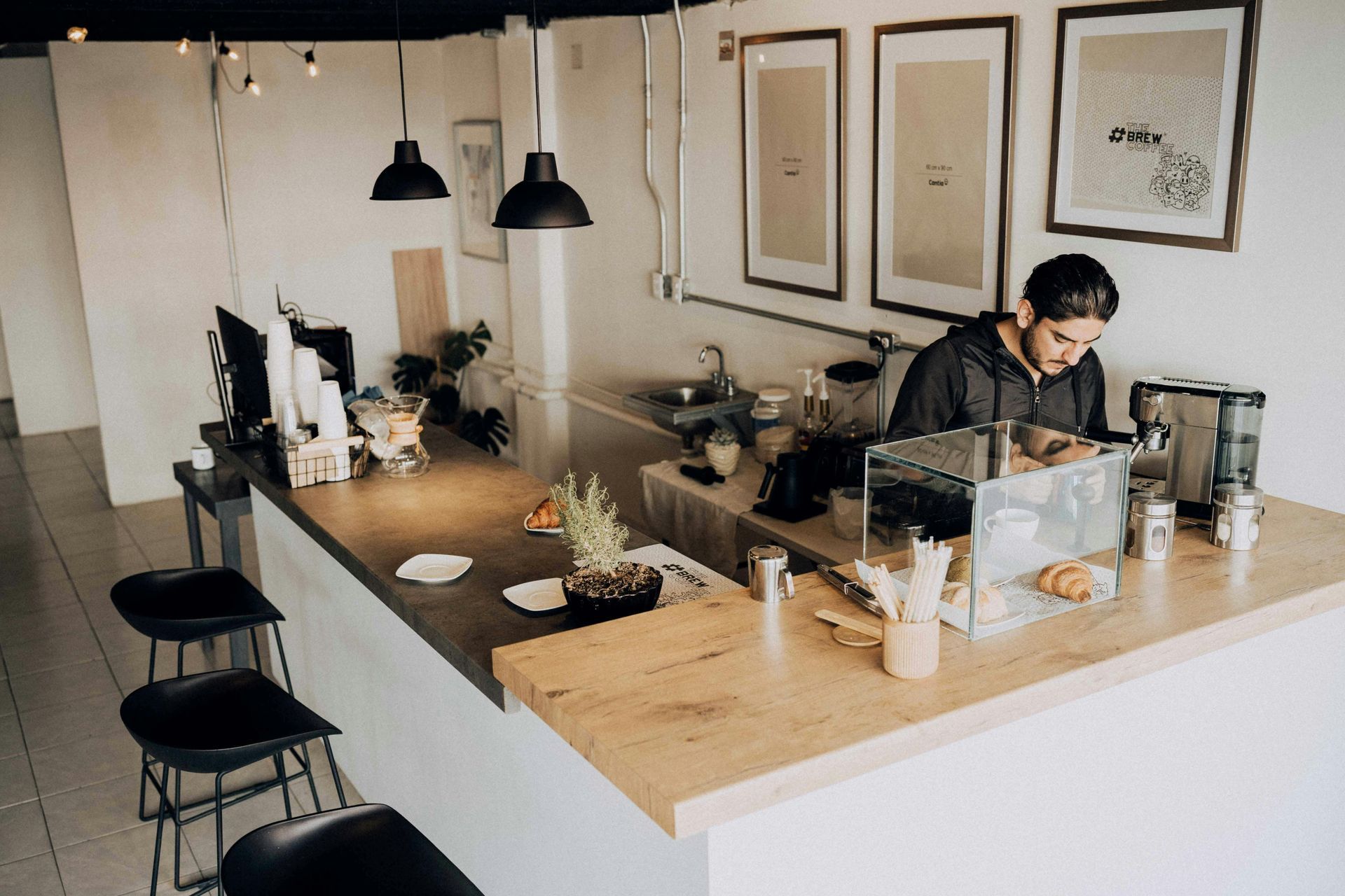 Minimal coffee shop interior with a barista preparing drinks behind a counter