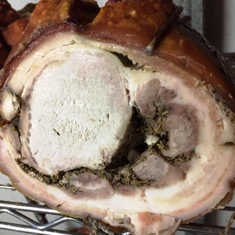 Un prodotto a base di carne di maiale arrosto, confezionato sottovuoto, con un'etichetta raffigurante l'illustrazione di un maiale, in una scatola di cartone.